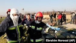 Rescue workers carry the body of a victim of an Ukrainian plane crash in Shahedshahr, southwest of the capital Tehran, Iran, Wednesday, Jan. 8, 2020.