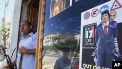 A Libyan rebel stands by a shop window decorated with a portrait of Muammar Qaddafi with his son Saif al-Islam on his shoulders in Tripoli.