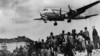 Американски самолет &quot;Дъглас C-54 Скаймастер&quot; доближава пистата на летище Темпелхоф, очакван с надежда от хората на земята. Снимката е от 10 август 1948 г. Въздушният мост е осъществяват в продължение на 15 месеца, след като Съветските власти отрязват Берлин от света. По време на операцията загиват 101 участници, сред които 40 британци и 31 американци.&nbsp;
