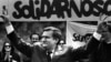 Poland -- Solidarity founding leader Lech Walesa shows v-sign in front of Solidarity poster during his presidential campaign in Plock, May 7, 1989