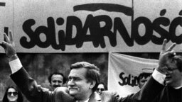 Poland -- Solidarity founding leader Lech Walesa shows v-sign in front of Solidarity poster during his presidential campaign in Plock, May 7, 1989