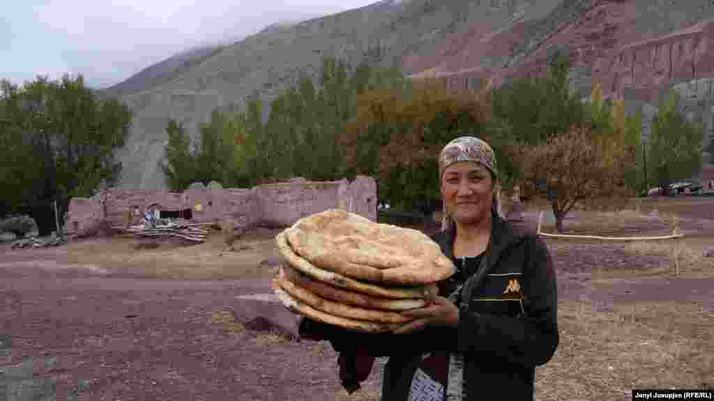 A woman poses with her bread in front of ruins. Not long after the deportations, a landslide destroyed the school, homes, and most of the agricultural land. Some of the houses still stand in ruins -- a daily reminder of those tragic events. Some of the deported villagers returned to Depshaar after about 15 years and started a new life here.