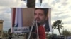 Workers hang a poster of Prime Minister Saad Hariri with Arabic words that read, "We are all Saad," on a seaside street in Beirut, Lebanon, Thursday, Nov. 9, 2017.