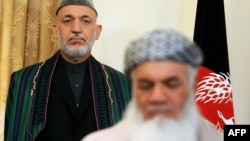 Water and Energy Minister Mohammad Ismail Khan (front) signs a document as Afghan President Hamid Karzai looks on at the presidential palace in Kabul in 2010.