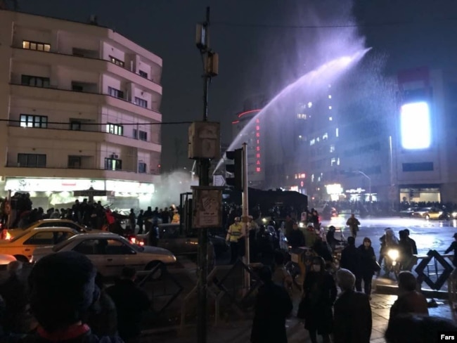 Authorities try to disperse demonstrators by using a water cannon in Ferdowsi Square on December 31.
