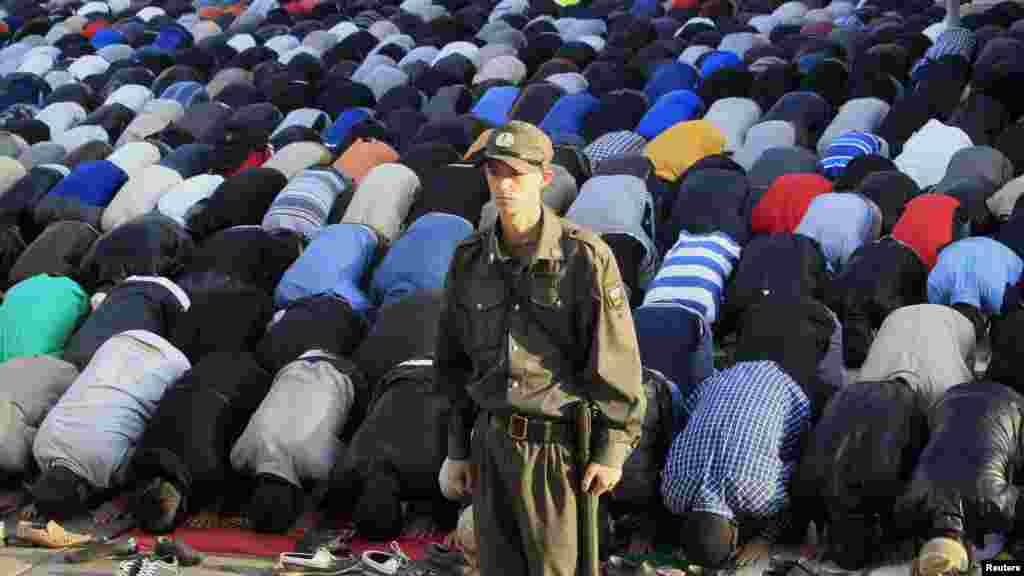 A Russian Interior Ministry member stands guard while Muslims pray to celebrate Eid al-Fitr in Moscow.