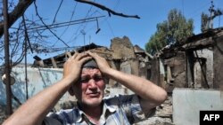 An ethnic Uzbek man stands beside the wreckage of his burned-out home in Osh on June 14, 2010.