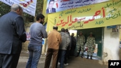 Soldiers stand guard as voters line up at a polling station in the Manial neighbourhood of Cairo.