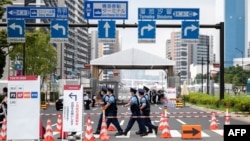 Полицейские проходят мимо одного из входов в Олимпийскую деревню в Токио 13 июля 2021 года.