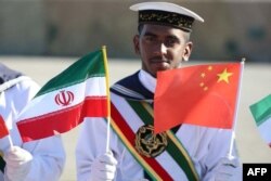 Иранский военный моряк держит флаги КНР и своей страны. Совместные военно-морские учения Китая и Ирана. Декабрь 2019 года.