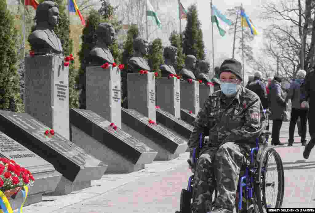 A disabled Ukrainian and veteran of the cleanup effort passes a monument honoring his fallen colleagues.