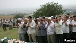 Chechnya -- People pray during the burial of Natalia Estemirova, a prominent human rights activist, at a cemetery in Koshkeldy, 70 km (44 miles) east of Grozny, July 16, 2009