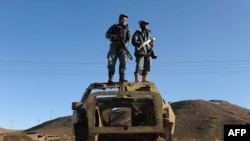 FILE: Two Afghan policemen keep watch atop the remains of a Soviet-era armored personnel carrier at Islam Qala border crossing with Iran in the western province of Iran.