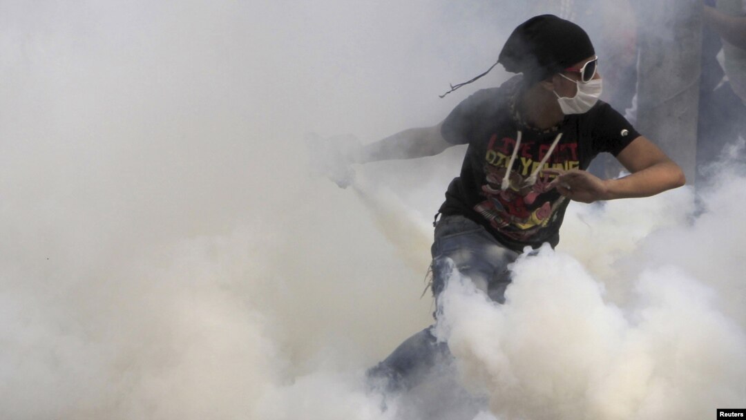 An antigovernment protester runs to throw a tear-gas canister back during clashes with Egyptian riot police on Tahrir Square in Cairo on November 27.