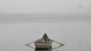 PAKISTAN - A man rows his boat in the waters of river Ravi engulfed in smog in Lahore on November 13, 2024.