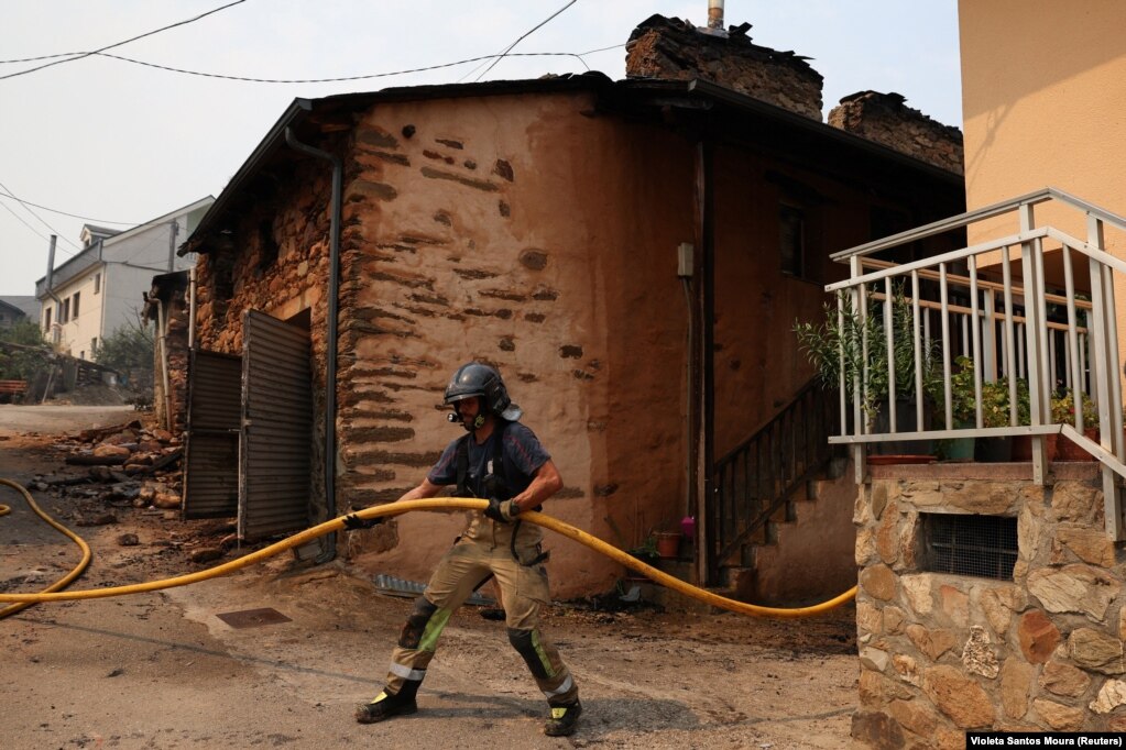 Një zjarrfikës duke u angazhuar pranë një shtëpie të djegur, pas një zjarri të egër në Las Medulas, Spanjë, më 11 gusht.