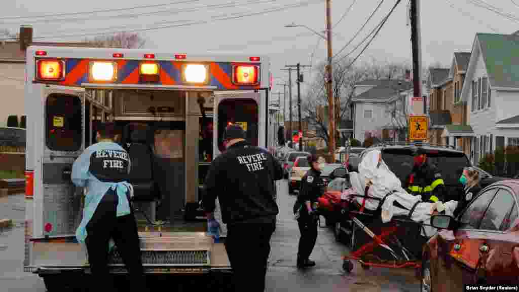 Medics and firefighters bring a patient to the ambulance amid the coronavirus disease (COVID-19) outbreak in Revere, Massachusetts, U.S.