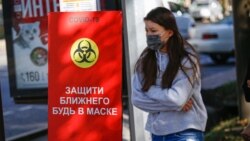 COVID-19 қаупі туралы жарнаманың жанынан өтіп бара жатқан адам. Алматы, 11 қыркүйек 2020 жыл.