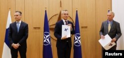 Ambasadorul Finlandei la NATO, Klaus Korhonen, secretarul general al NATO, Jens Stoltenberg, și ambasadorul Suediei la NATO, Axel Wernhoff, participă la o ceremonie pentru a marca cererea de aderare a Suediei și Finlandei la Bruxelles, Belgia, 18 mai 2022.