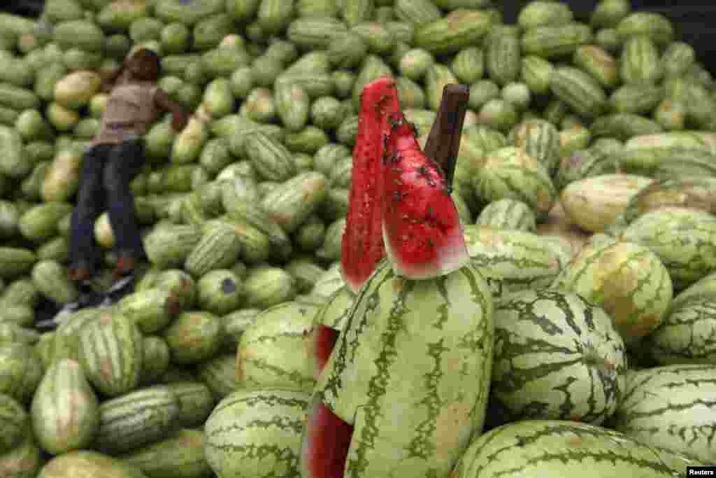 A roadside fruit vendor takes a nap at his makeshift stall as bees crawl on a slice of watermelon on display in Karachi, Pakistan. (Reuters/Athar Hussain)