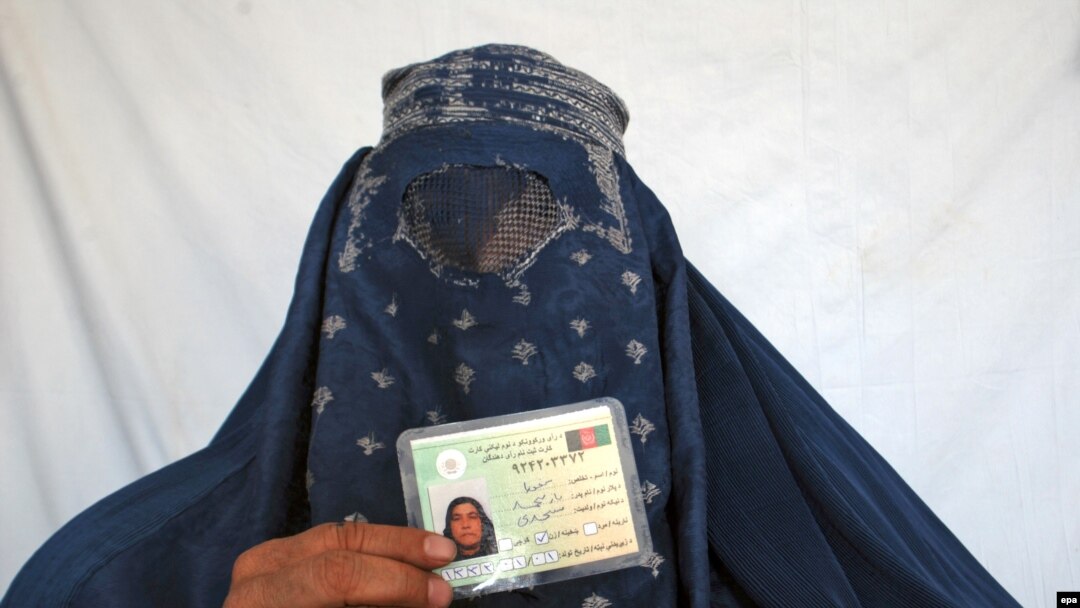 An Afghan woman shows her voter registration card.
