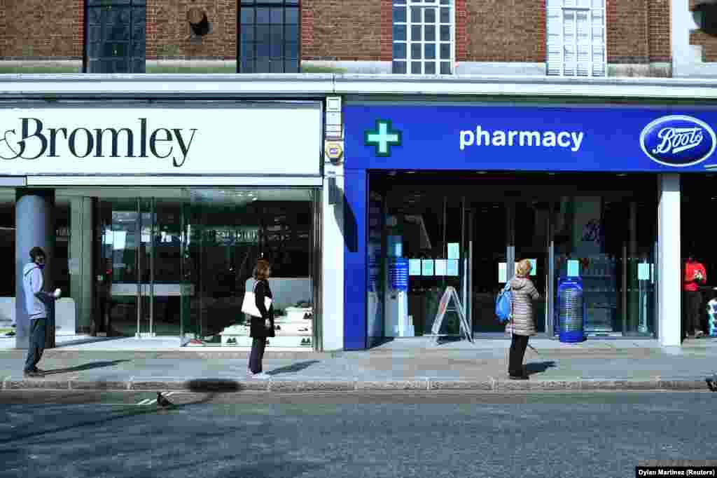 U.K. - People stand apart as they follow social distancing while they queue outside a Boots pharmacy shop, as the spread of coronavirus disease (COVID-19) continues in London, 24March2020