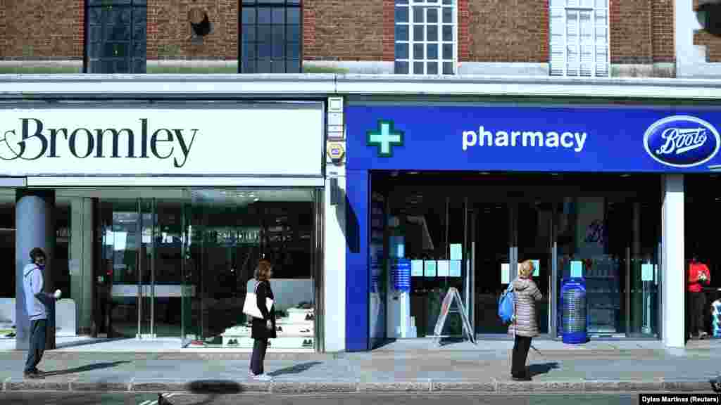 U.K. - People stand apart as they follow social distancing while they queue outside a Boots pharmacy shop, as the spread of coronavirus disease (COVID-19) continues in London, 24March2020