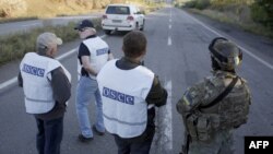 Український військовослужбовець і спостерігачі місії ОБСЄ на дорозі біля Донецька, вересень 2014 року