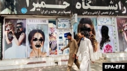 آرشیف - دو مرد در حال عبور از مقابل یک آرایشگاه در کابل. عکس از آرشیف