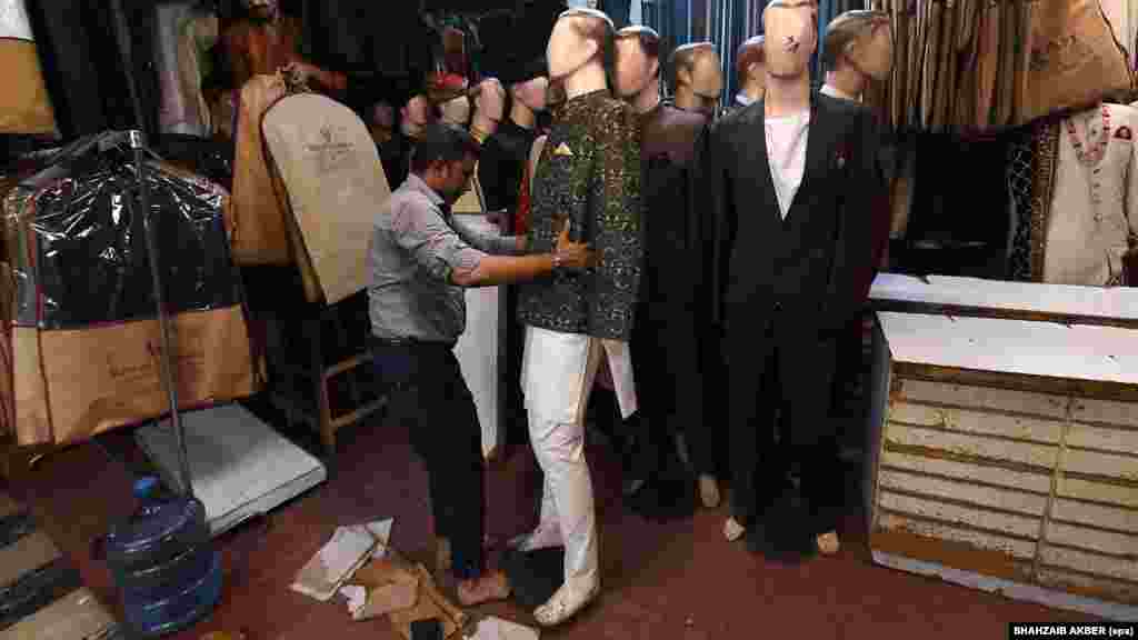 Radnik u prodavnici u Karačiju, u Pakistanu, oblači lutke za izloge usred naredbe o ranijem zatvaranju. Pakistanska vlada je naložila da se prodavnice zatvaraju do 21 sat u nastojanju da se uštedi energija usred rata na Bliskom istoku.