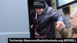 Представник «Капеланського патруля» допомогає вийти з броньованого транспорту евакуйованим 