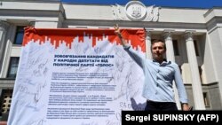 Святослав Вакарчук у здания Верховной рады Украины со списком обязательств депутатов его партии 