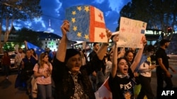 Protestatari țin steaguri europene și ale Georgiei în timp ce mărșăluiesc pe străzile din Tbilisi în semn de protest după ce parlamentarii au promovat o lege controversată al „agenților străini”, 22 aprilie 2024.