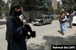 Taliban fighters stand guard at a checkpoint in Kabul on August 18.