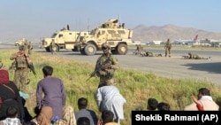Американські солдати стримують тих, хто намагається потрапити на летовище, щоб втекти з Афганістану, який захопили таліби. Величезна кількість людей спричинила хаос, що утруднило евакуації. Міжнародний аеропорт Кабула. 16 серпня 2021 року