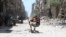 SYRIA - A boy sits on a chair along a damaged street at the city of Douma in Damascus, Syria April 16, 2018.