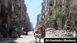 Дума шаарынын чок ортосунда отурган бала. Сирия, 16-апрель, 2018-жыл. 