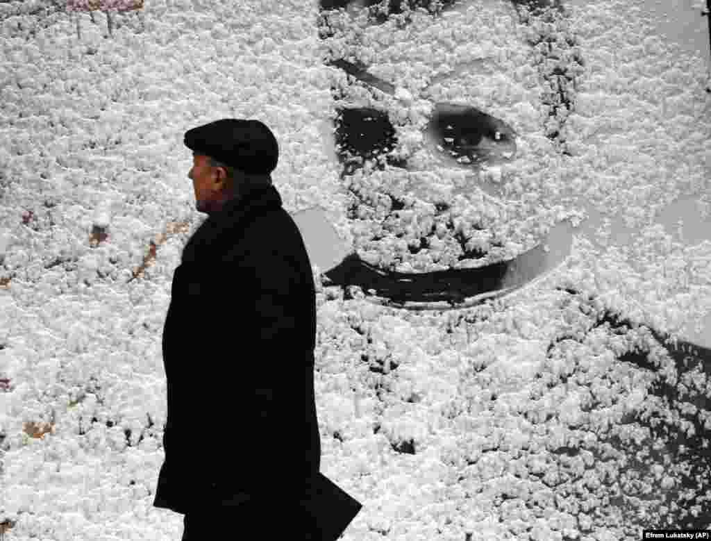 A man passes by a big board covered with snow in central Kyiv.&nbsp;(AP/Efrem Lukatsky)