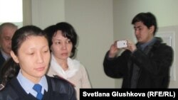 Экс-председателя агентства по статистике Анар Мешимбаеву (в центре) ведут в зал суда. Астана, 27 января 2014 года. 
