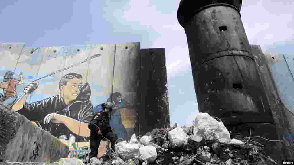 An Israeli border officer stands on a pile of rubble from a damaged section of Israel&#39;s controversial barrier at the Aida refugee camp in the West Bank town of Bethlehem. (Reuters/Ammar Awad)