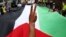 Një demonstrues bën simbolin e fitores përpara një flamuri palestinez gjatë një proteste kundër një prej aksioneve ushtarake të Izraelit në Gaza. Fotografi ilustruese nga arkivi.