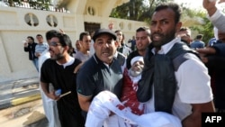 People assist a man who was injured after Libyan militiamen opened fire on a crowd wanting them to move out of their headquarters on November 15 in southern Tripoli. 