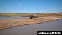 Трактор, проезжающий по переправе через реку Селета в селе Приречное. Акмолинская область, 20 апреля 2021 года.