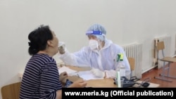Медработник в защитной одежде проводит осмотр пациента во время пандемии нового коронавируса. 