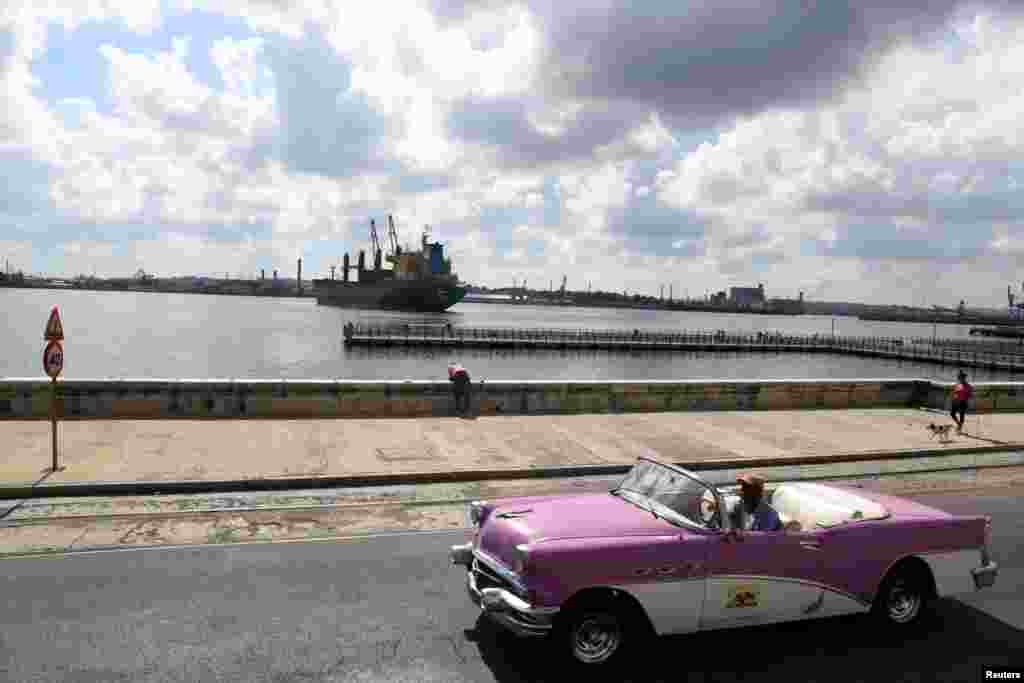 Havanna kikötője mellett halad el épp egy klasszikus kabrió. Sok kubai utazási iroda városnéző túrákat és kirándulásokat is kínál ezekkel az autókkal