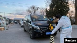 Un angajat al unui crematoriu din Beijing stă în fața unei cozi de mașini funebre din fața clădirii. 