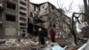 Locuitori din Donețk trec pe lângă un bloc de apartamente distrus de un atac rusesc cu rachete la Selîdove, regiunea Donețk - 16 februarie 2024. 
