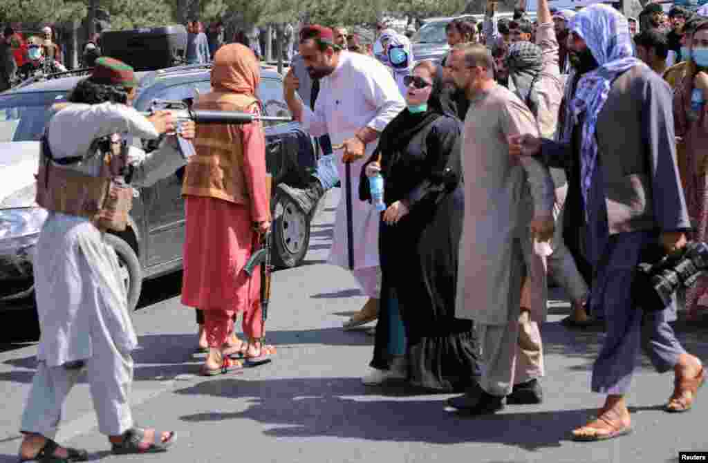 یک طالب مسلح در مقابل سفارت پاکستان در کابل سلاحش را به طرف یکی از زنان معترض گرفته است. 
