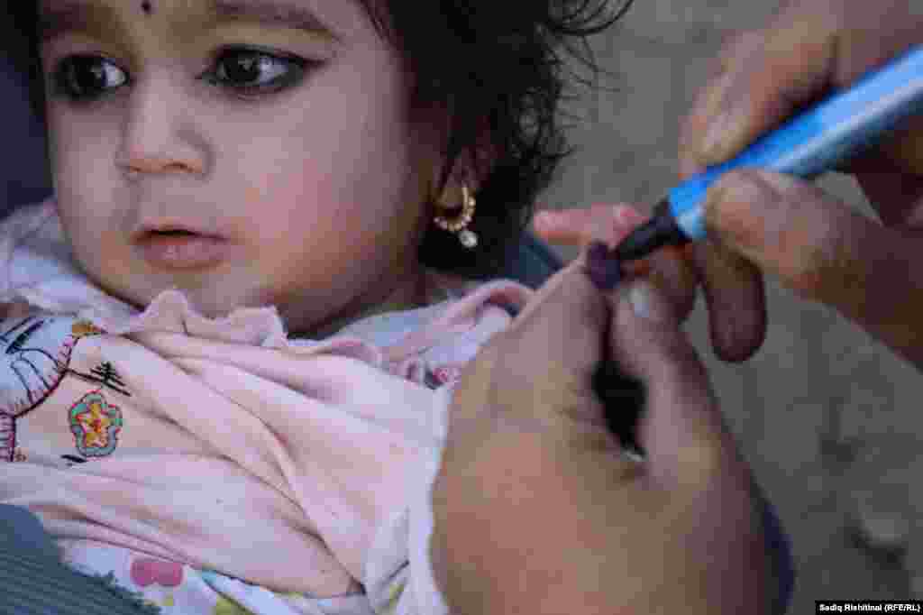 A polio worker administers a vaccine to a child in Kandahar, Afghanistan.