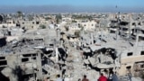 Palestinians look at the houses destroyed in Israeli strikes during the conflict, at Khan Younis refugee camp